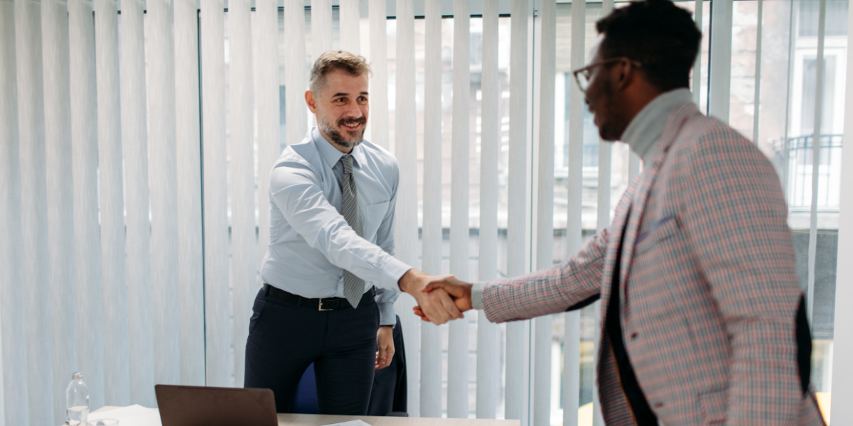 Zwei Männer schließen Gehaltsverhandlung mit Handschlag im Büro ab