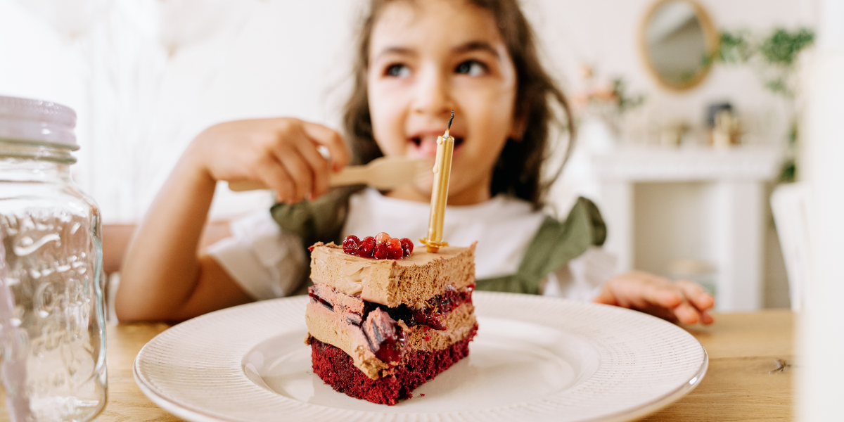 Ein Kind isst ein Stück Kuchen am Tisch