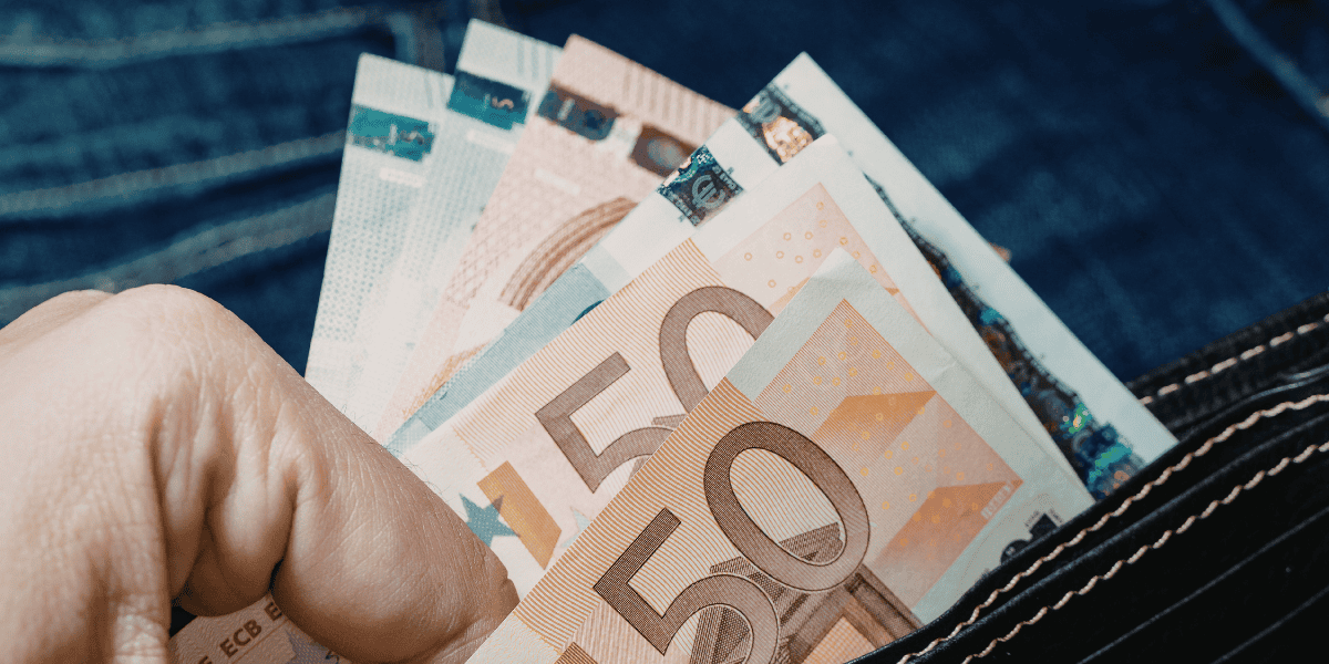 Hand hält mehrere Euro-Banknoten (50-Euro-Scheine sichtbar) in einer offenen Geldbörse vor Jeansstoff-Hintergrund