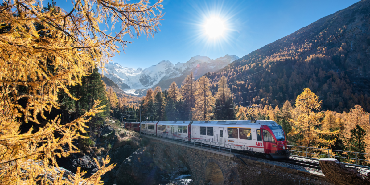 Zug fährt durch herbstliche Berglandschaft