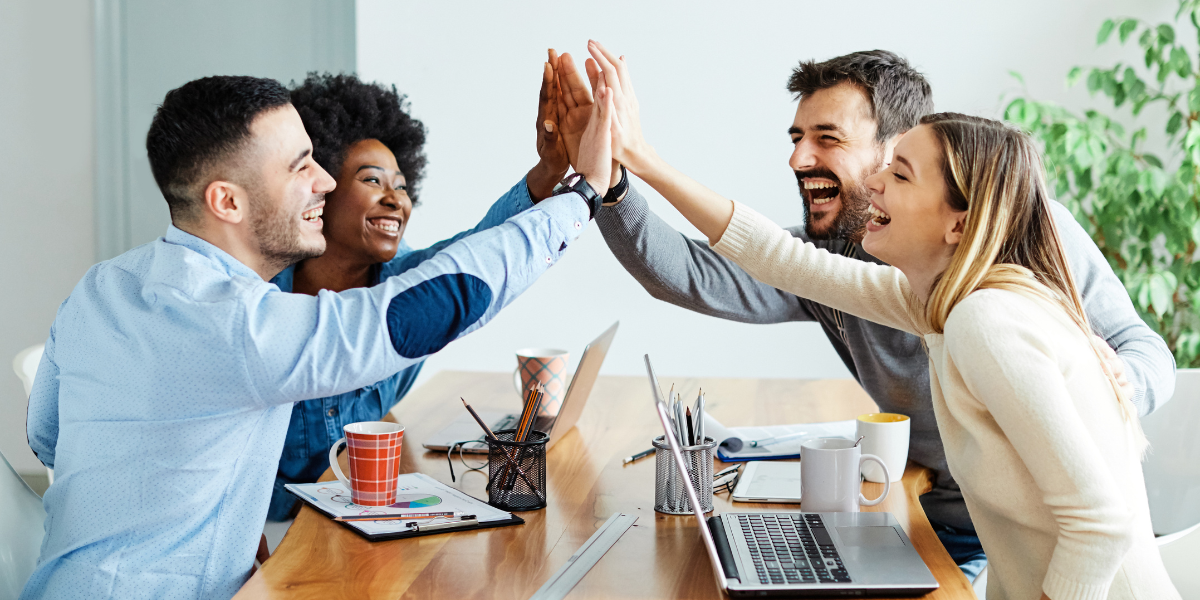 Team feiert gemeinsamen Erfolg mit High Five im Büro