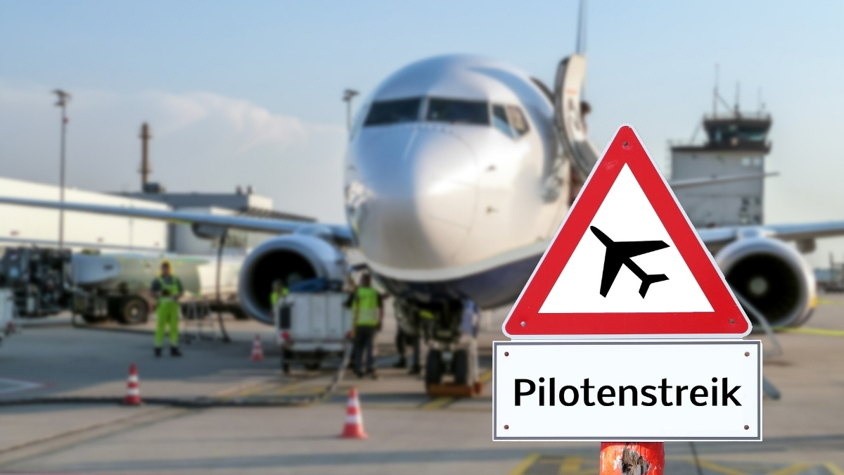 Warnschild mit Flugzeugsymbol und der Aufschrift „Pilotenstreik“ vor einem Flugzeug auf dem Rollfeld