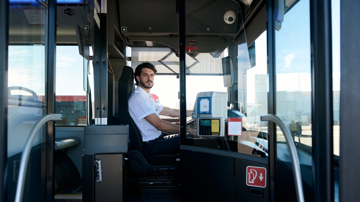 Busfahrer sitzt im Fahrerbereich eines Linienbusses und blickt nach vorne