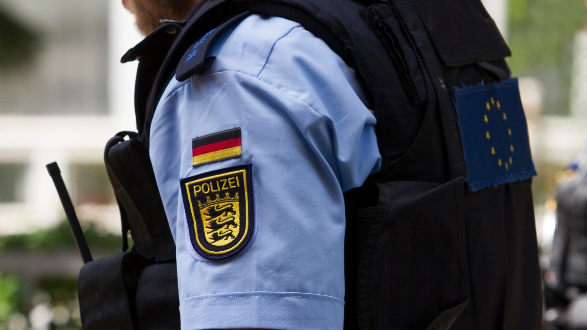 Nahaufnahme eines deutschen Polizeibeamten in Uniform mit Abzeichen und EU-Flagge auf der Schutzweste