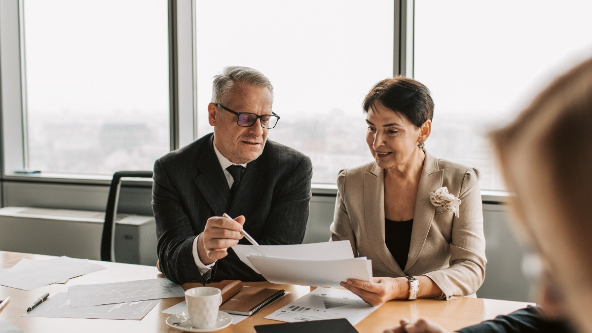 Ein Berater bespricht gemeinsam mit einer Kundin Dokumente am Tisch in einem Büro