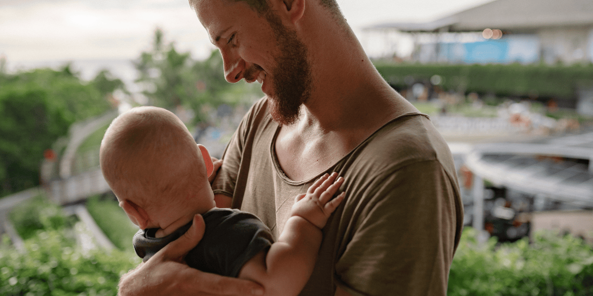 Vater hält sein Baby im Arm und lächelt