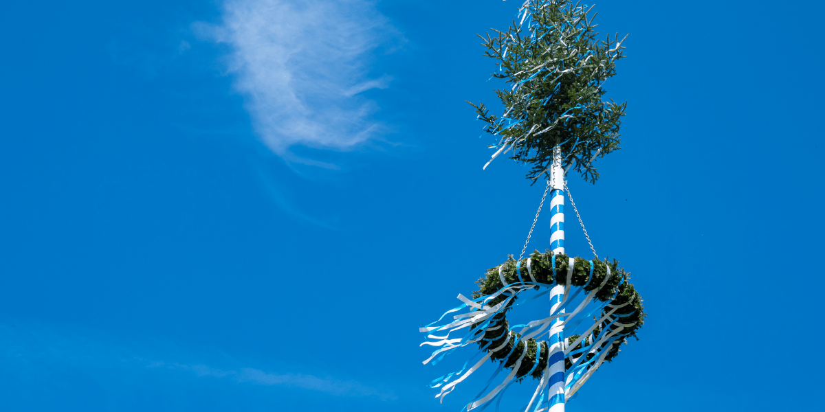 maibaum mit dekoration vor blauem himmel