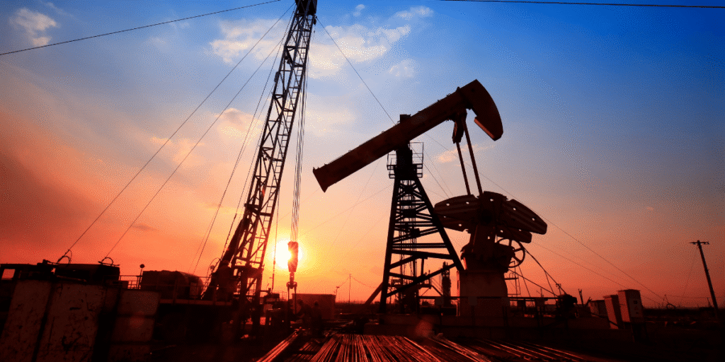 Ölpumpe und Bohranlage als Silhouette bei Sonnenuntergang auf einem Fördergelände
