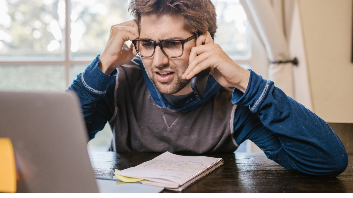 Mann mit Brille telefoniert am Laptop und wirkt angespannt
