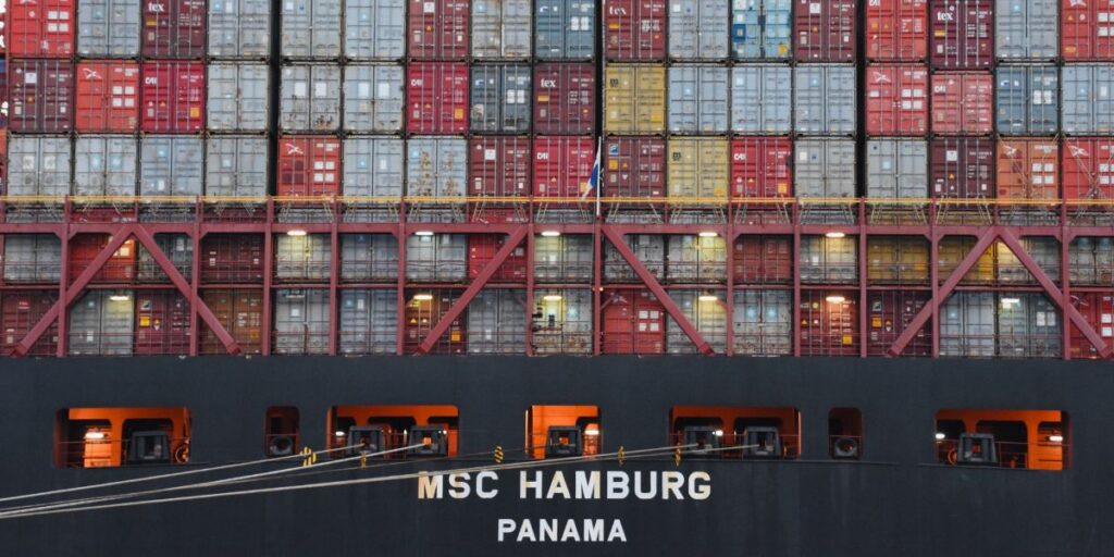 Containerschiff mit gestapelten Frachtcontainern im Hafen.