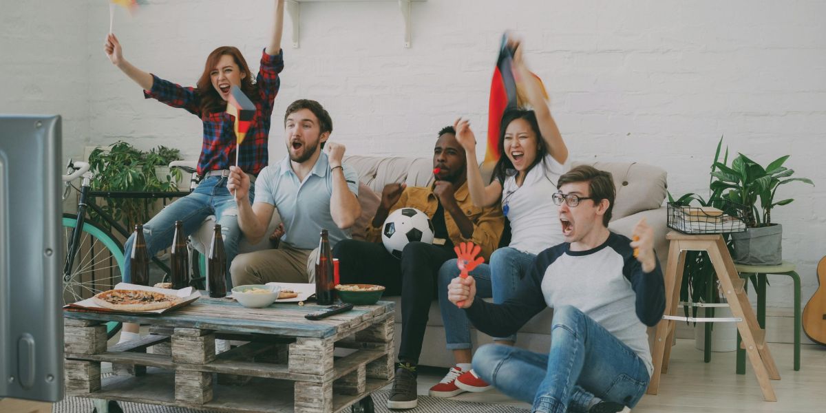 Fünf Fußballfans fiebern vor dem Fernseher mit ihrem Lieblingsteam mit