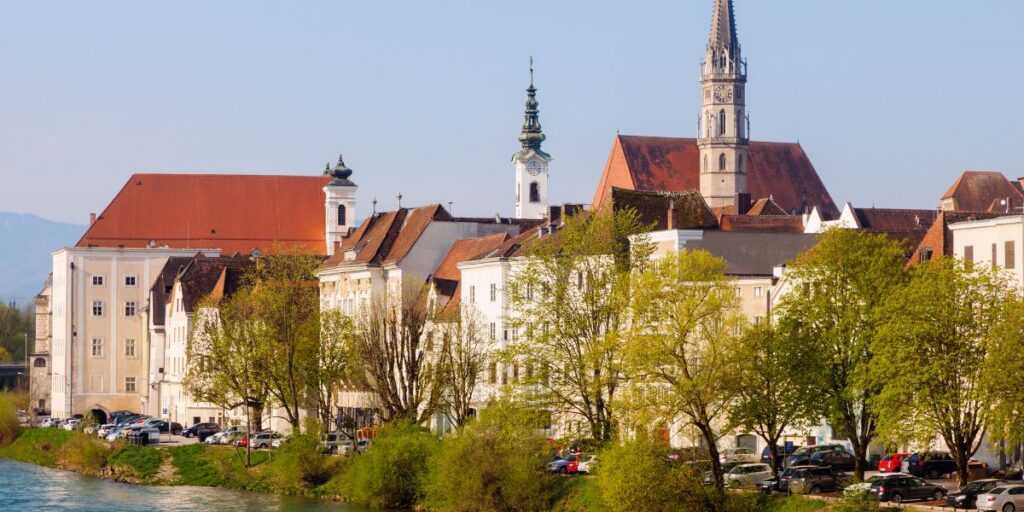 Blick auf die Altstadt von Steyr in Oberösterreich mit historischen Gebäuden und Kirchtürmen entlang des Flusses.