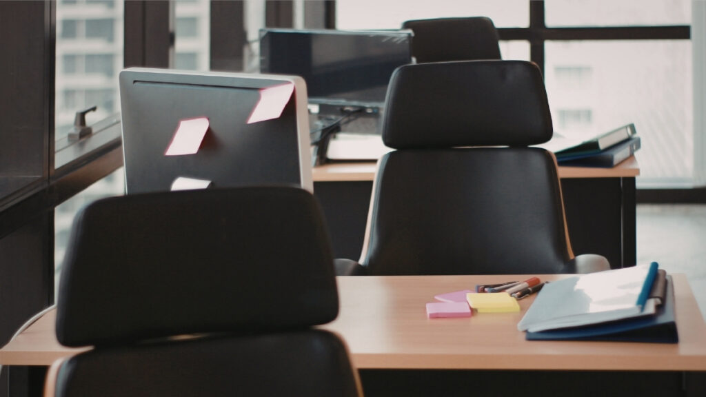 Leere Arbeitsplätze mit Stühlen, Monitoren und Unterlagen in einem Büro