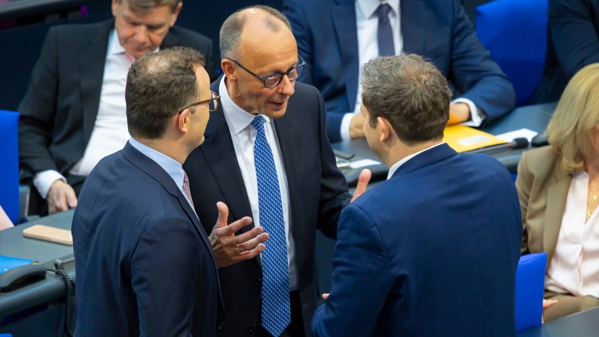 Drei Männer sprechen in einer Parlamentsdebatte miteinander.