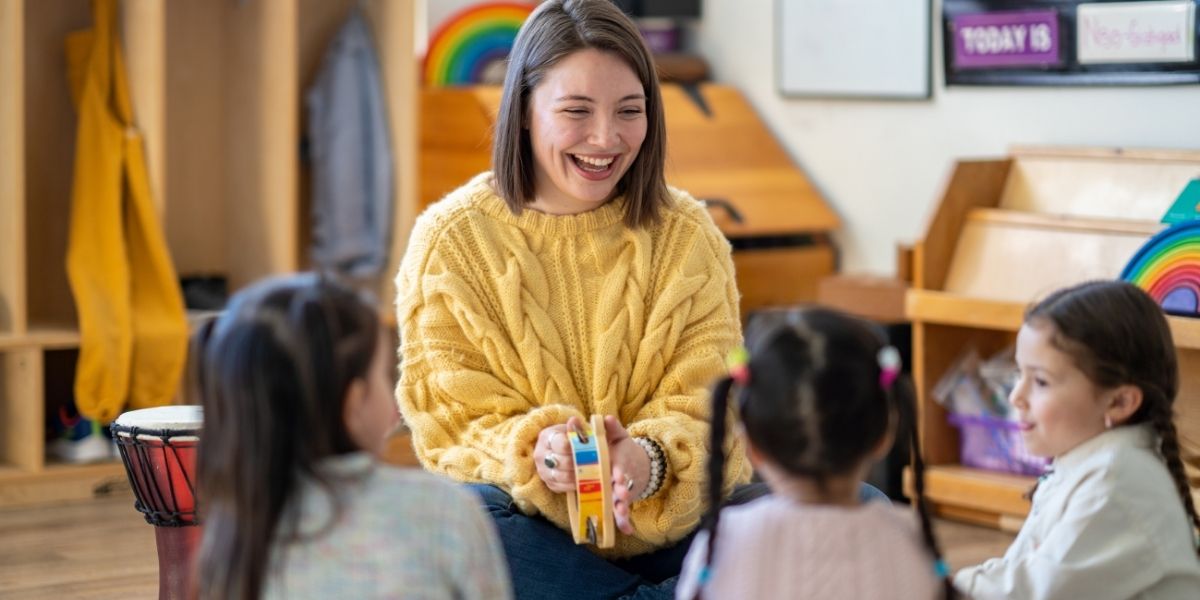 Eine erwachsene Person spielt mit drei Kindern.