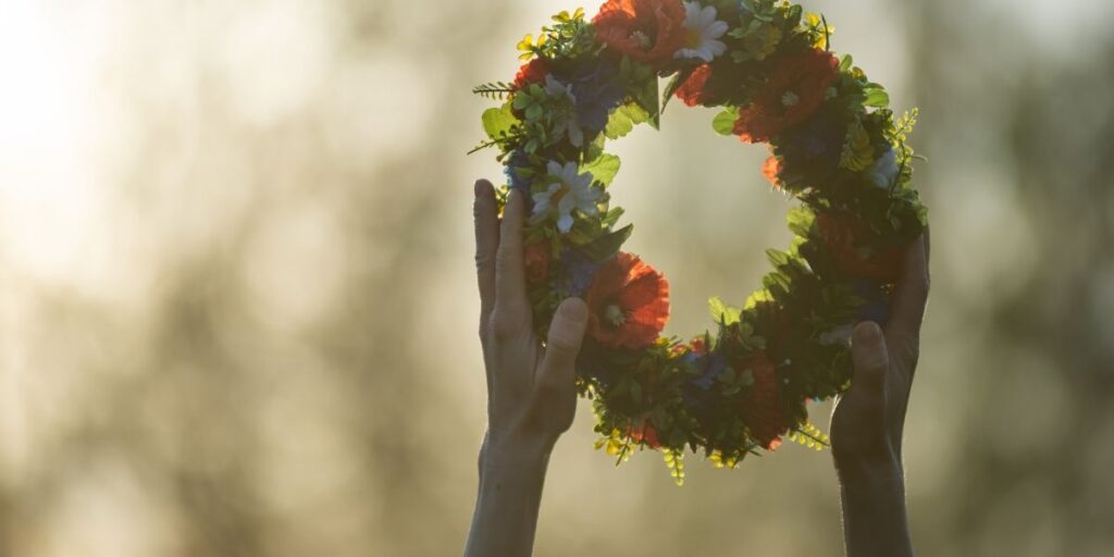 hände mit midsommar kranz im abendlicht.