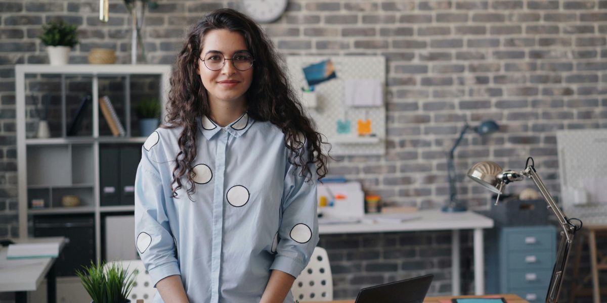 Junge Frau mit dunklen Locken steht in einem modernen Office