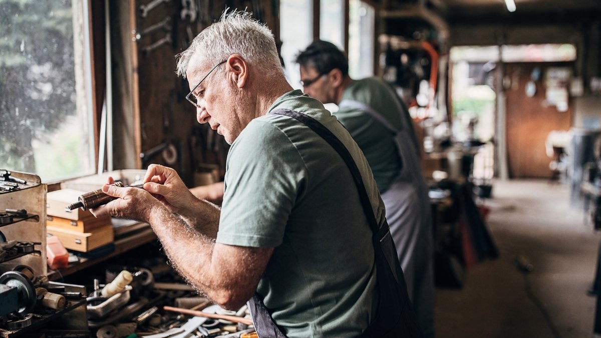 Älterer Mann arbeitet konzentriert an einem Werkstück in einer Werkstatt