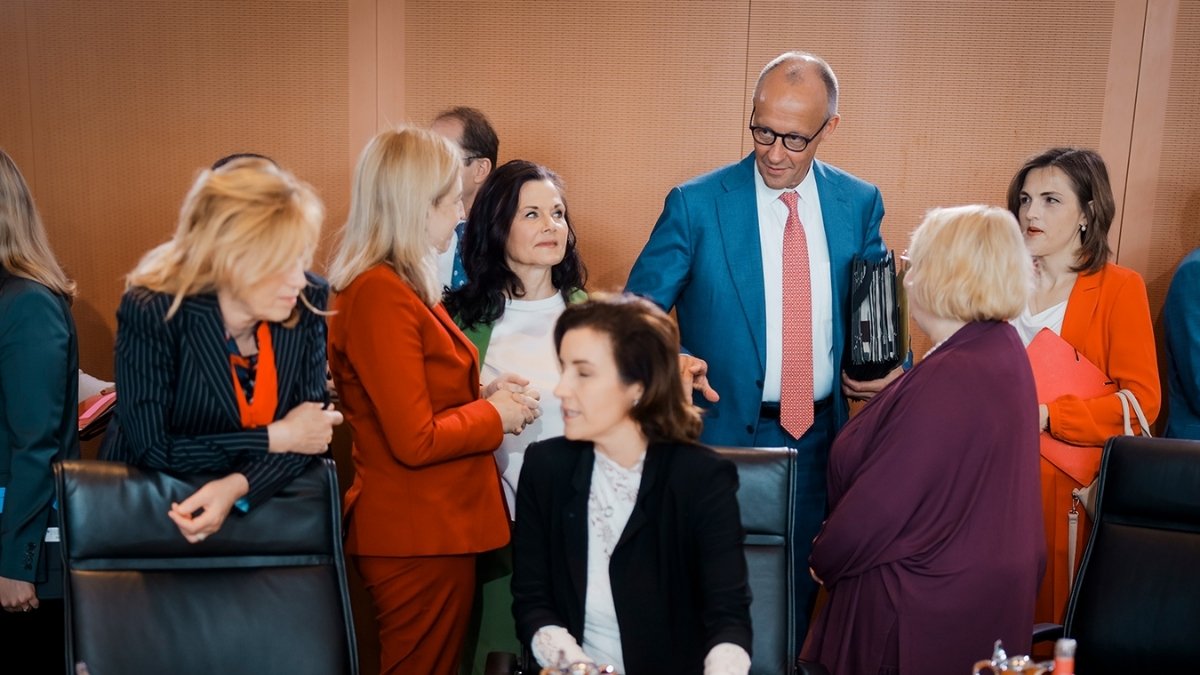 Friedrich Merz spricht in einer Gruppe von Personen in einem Konferenzraum.