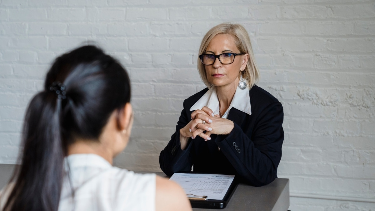 Zwei Frauen sitzen sich in einem Vorstellungsgespräch an einem Tisch gegenüber