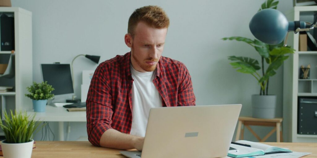 Ein junger Mann sitzt an einem Laptop und guckt konzentriert