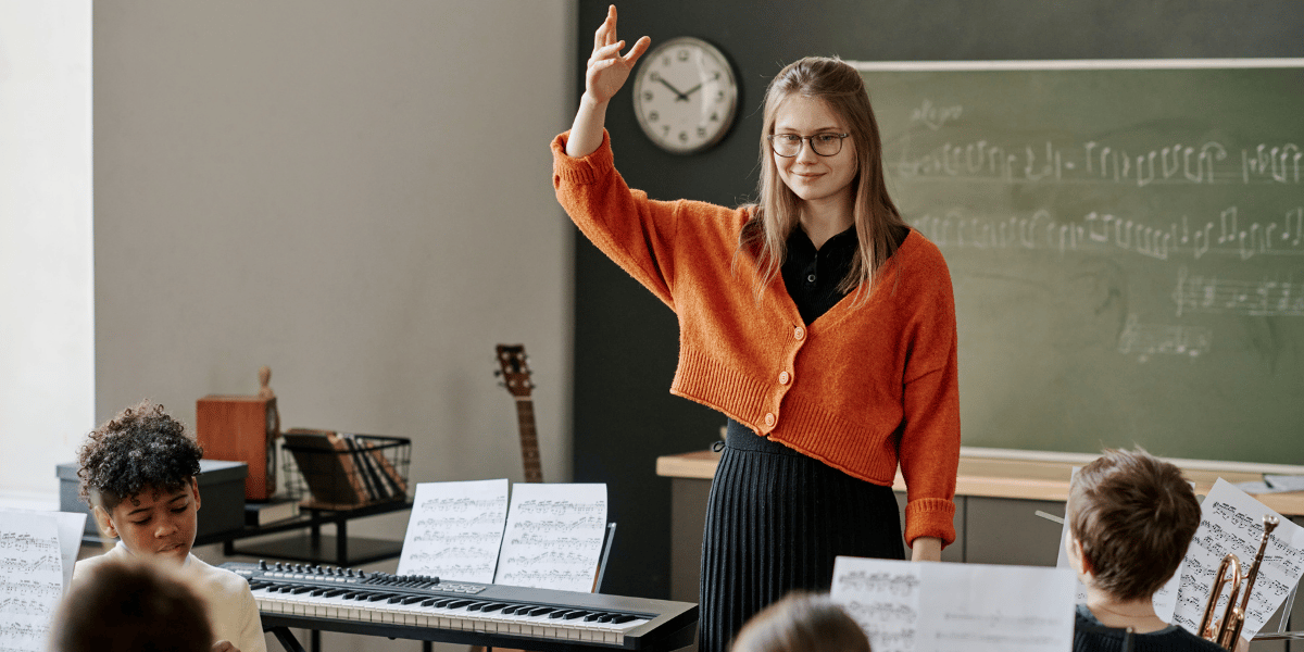 Eine Musiklehrerin dirigiert eine Schulklasse.