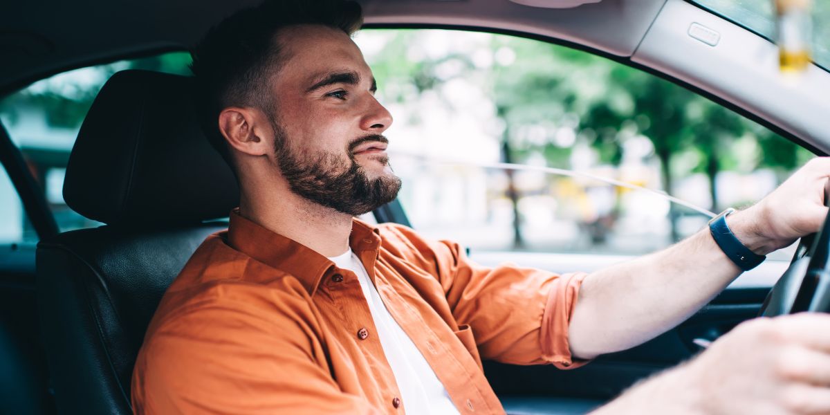 Ein Mann sitzt am Steuer eines Autos und fährt.