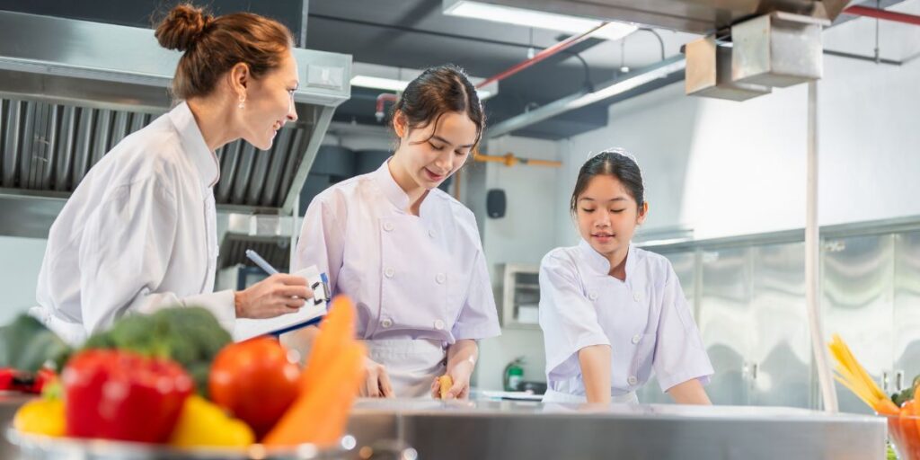 Drei Auszubildende arbeiten gemeinsam in einer professionellen K&uuml;che.