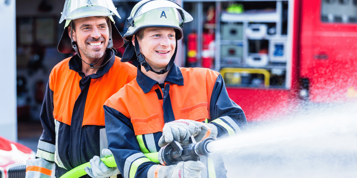 Zwei Feuerwehrmänner mit einem Schlauch.